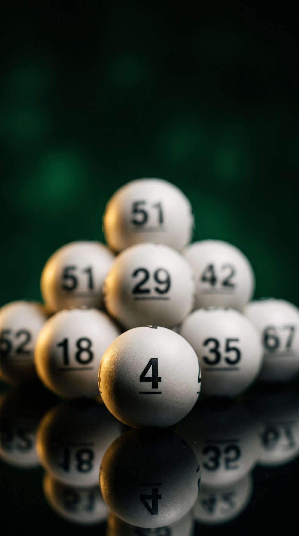 Bolas de loteria numeradas empilhadas sobre uma superfície escura que reflete